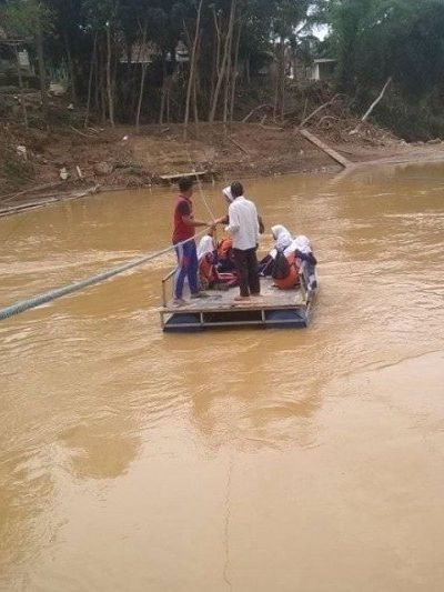 Pelajar SMPN 4 Sajira menggunakan rakit penyeberangan melintasi Sungai Ciberang karena jembatan terputus akibat banjir bandang. Foto: ANTARA/Mansyur S