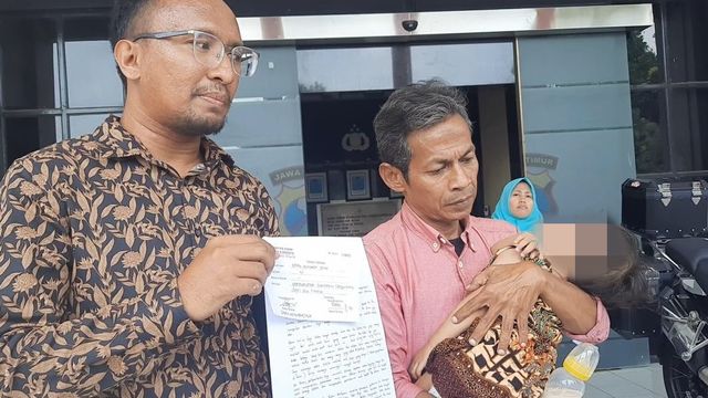 Suami tersangka penghina Risma, Daru Asmara Jaya (kanan) dan anaknya berusia 2 tahun Foto: Yuana Fatwalloh/kumparan