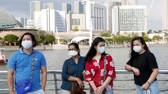 Turis memakai masker saat mengunjungi Merlion Park di Singapura. Foto: REUTERS/Feline Lim