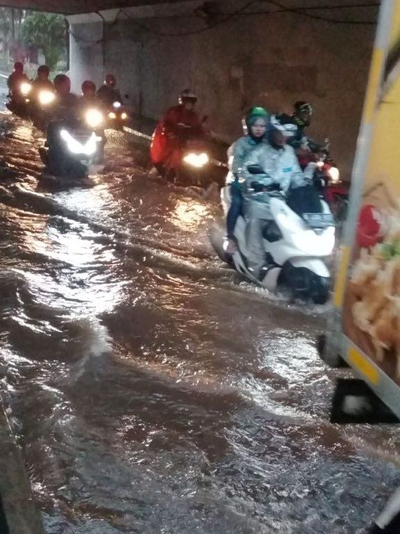Sejumlah pengendara motor melintasi banjir di Kolong Semanggi, Jakarta, Sabtu (8/2).  Foto: Twitter/ @TMCPoldaMetro