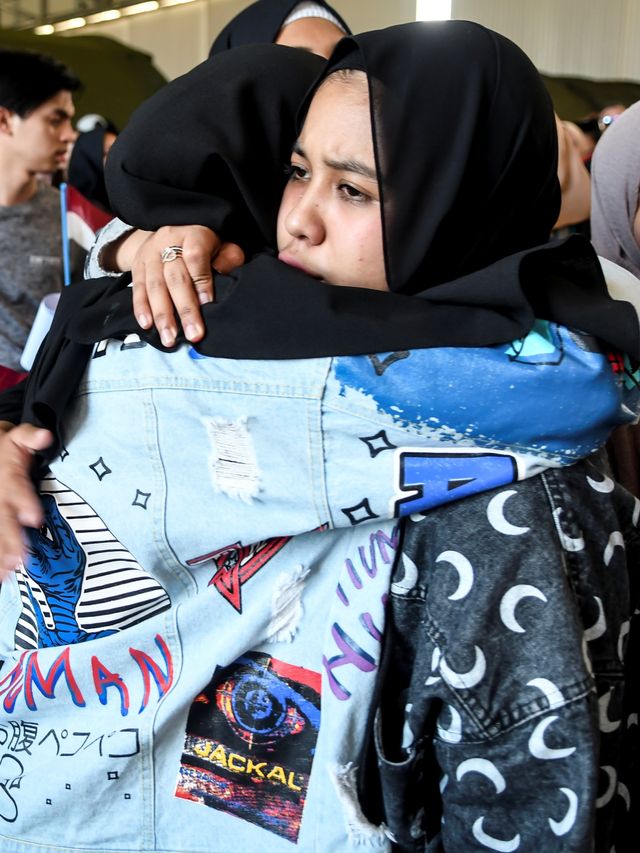 Warga Negara Indonesia berpelukan saat akan meninggalkan ruang observasi di Hanggar Pangkalan Udara TNI AU Raden Sadjad, Ranai, Sabtu (15/2). Foto: ANTARA FOTO/Muhammad Adimaja