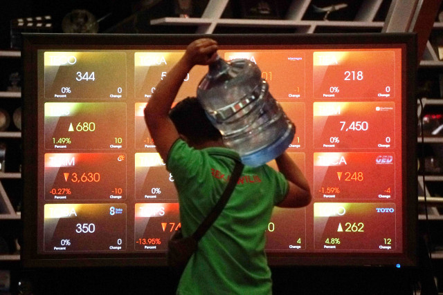 Pekerja melintas layar monitor Indeks Harga Saham Gabungan (IHSG). Foto:  Irfan Adi Saputra/kumparan