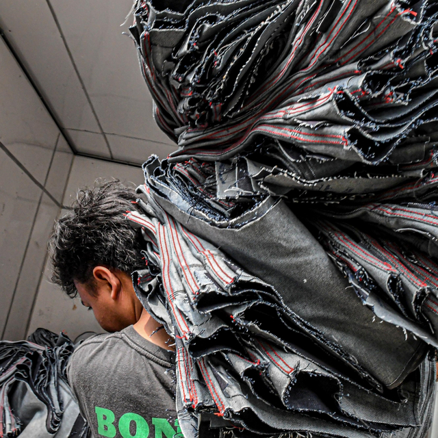 Pekerja mengangkat tumpukan tekstil di Jakarta. Foto: ANTARA FOTO/Muhammad Adimaja