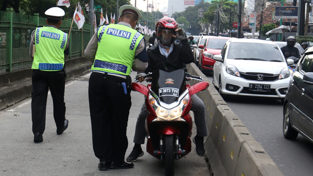 Polisi menilang pemotor yang menerobos jalur TransJakarta di kawasan Pasar Rumput. Foto: Iqbal Firdaus/kumparan