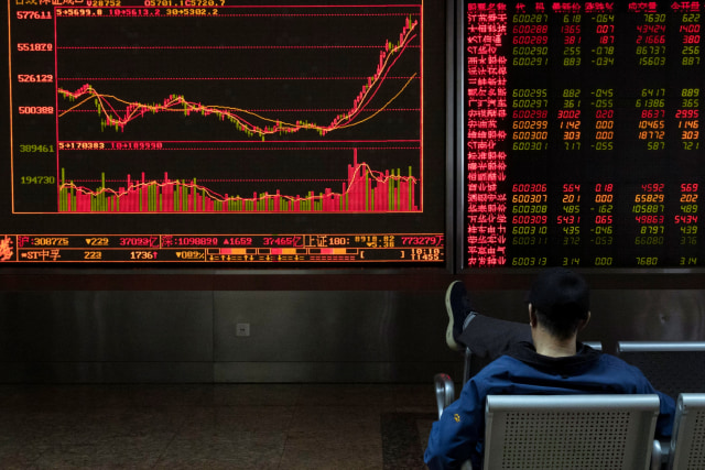 Seorang warga memantau pergerakan harga saham di Beijing, China. Foto: AP Photo / Ng Han Guan