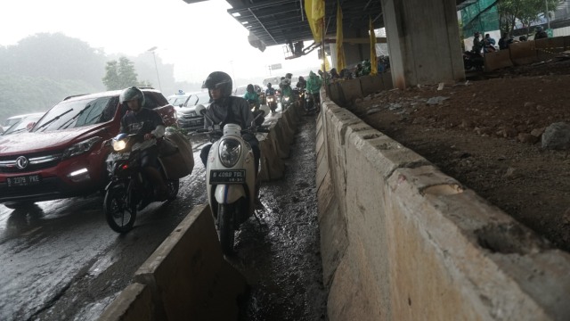 Sejumlah pengendara motor berteduh dari hujan di bawah kolong proyek LRT kawasan Jakarta Timur (2/21). Foto: Iqbal Firdaus/kumparan 