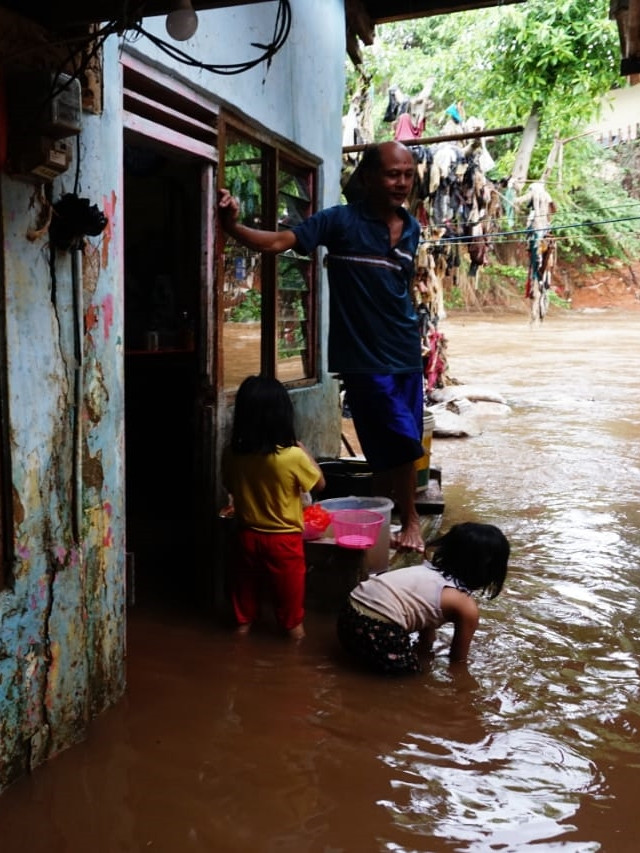 Warga mengawasi anaknya yang bermain ai saat banjir di kawasan Kampung Melayu, Jatinegara. Foto: Jamal Ramadhan/kumparan