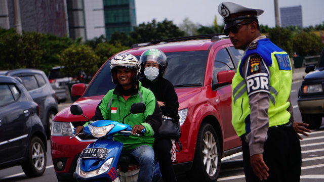 Polisi mengatur lalu lintas saat sepeda motor melintas di dalam tol untuk menghindari banjir di kawasan Kelapa Gading, Sunter dan Cempaka Putih. Foto: Jamal Ramadhan/kumparan