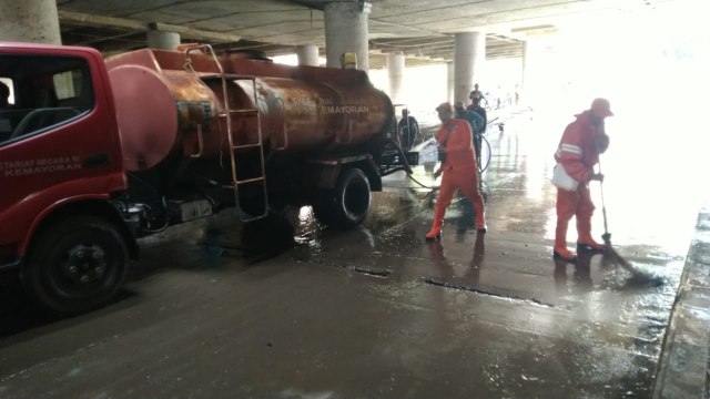 Petugas PPSU membersihakan sisa banjir di underpass Kemayoran, Jakarta Pusat.  Foto: Fachrul Irwinsyah/kumparan