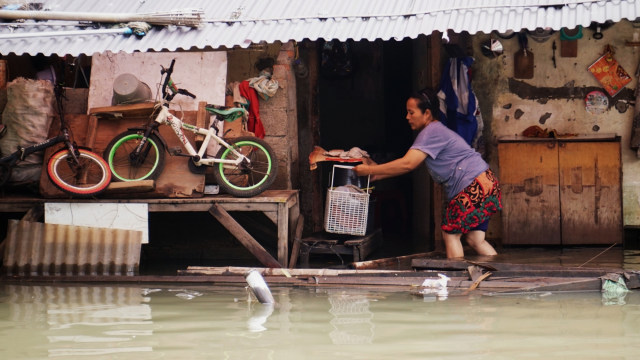 Seorang perempuan memindahkan barang-barang nya saat banjir di RW 03 Kelurahan Pegangsaan Dua, Kecamatan Kelapa Gading, Jakarta Utara, Senin (24/2). Foto: Jamal Ramadhan/kumparan