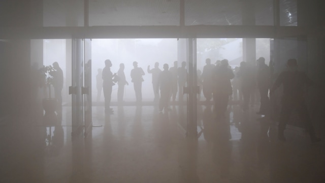 Sejumlah karyawan berada di luar gedung saat terjadi kepulan asap putih di Gedung Nusantara III, Kompleks Parlemen, Senayan, Jakarta, Senin (24/2). Foto: ANTARA FOTO/M Risyal Hidayat