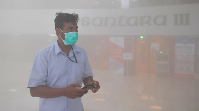 Karyawan berjalan keluar ruangan saat terjadi kepulan asap putih di Gedung Nusantara III, Kompleks Parlemen, Senayan, Jakarta, Senin (24/2). Foto: ANTARA FOTO/M Risyal Hidayat