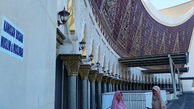 Salah satu pengumuman yang bertuliskan 'Kawasan Busana Muslim & Muslimah' di dinding Masjid Raya Sumbar (Foto: Irwanda/Langkan.id)