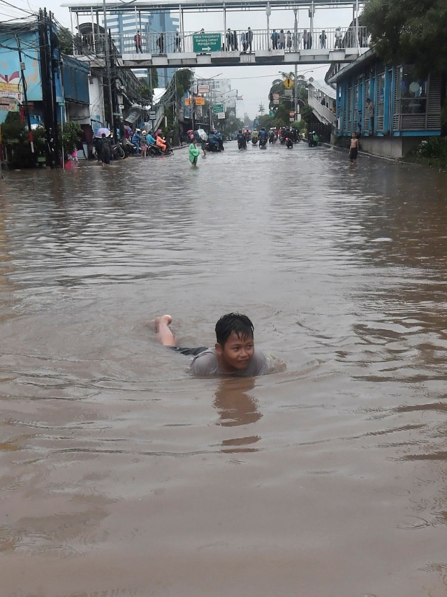 Seorang anak bermain saat banjir menggenangi Jalan Gunung Sahari, Jakarta Pusat, Selasa (25/2).  Foto: ANTARA FOTO/Fanny Octavianus