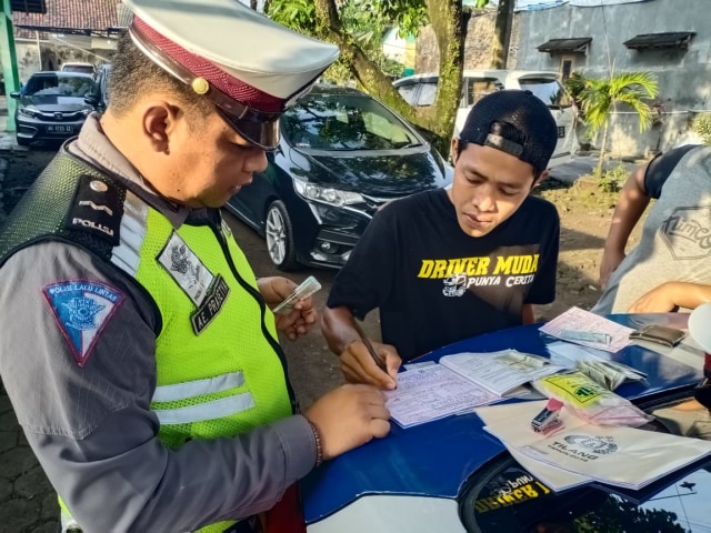Seorang polisi menindaklanjuti pengemudi yang membahayakan pengguna jalan. Foto: Erfanto.