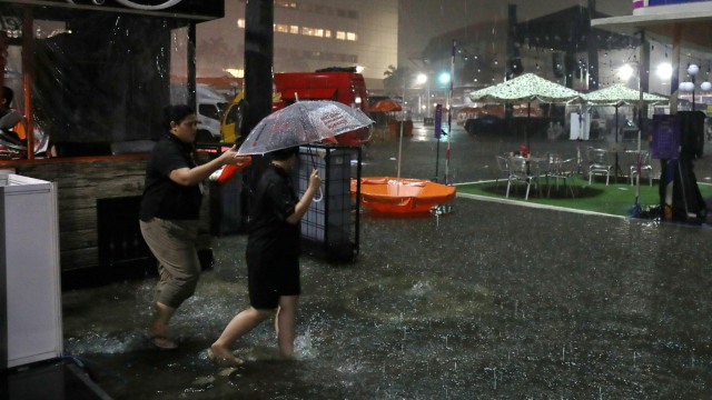 Pengunjung menggunakan payung melintas di tengah hujan saat BNI Java Jazz Festival 2020, di JIExpo Kemayoran, Jakarta, Minggu (1/3/2020). Foto: Nugroho Sejati/kumparan