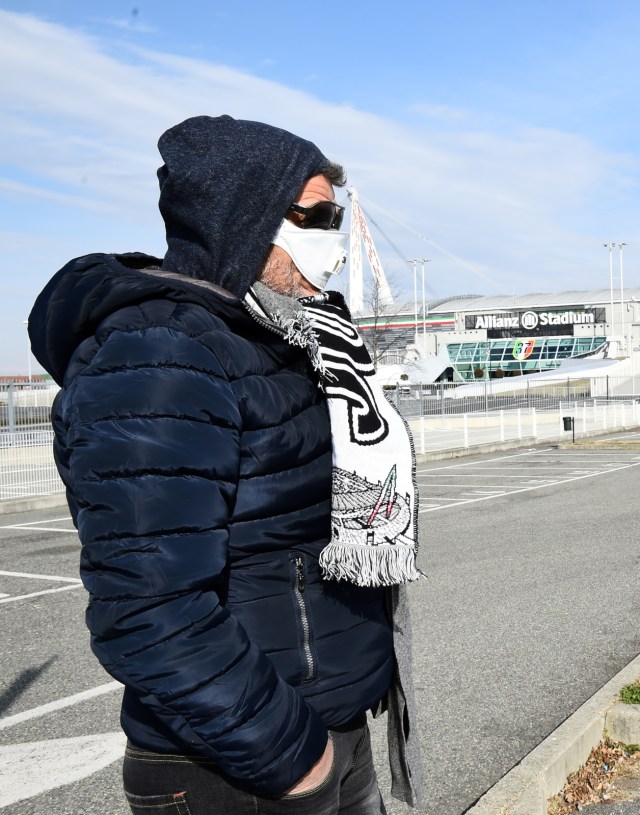Seorang pendukung Juventus mengenakan masker di luar Allianz Stadium. Foto: Reuters/Massimo Pinca