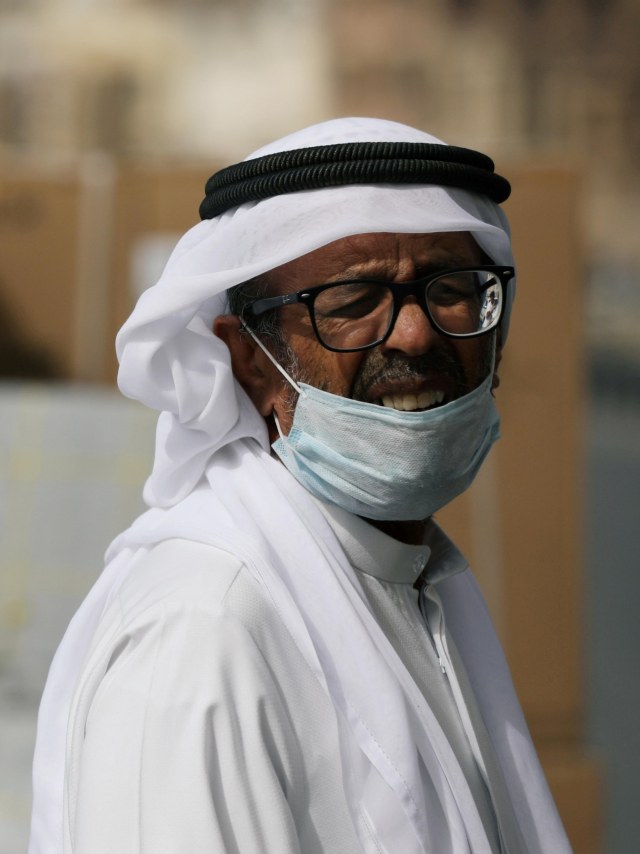 Seorang pekerja mengenakan masker saat menunggu barang dimuat, di Iran. Foto: REUTERS/Christopher Pike