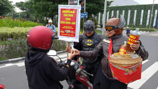 Batman dan Gundala memberikan jamu dan pamflet secara gratis kepada pengguna jalan. (Fernando Fitusia)
