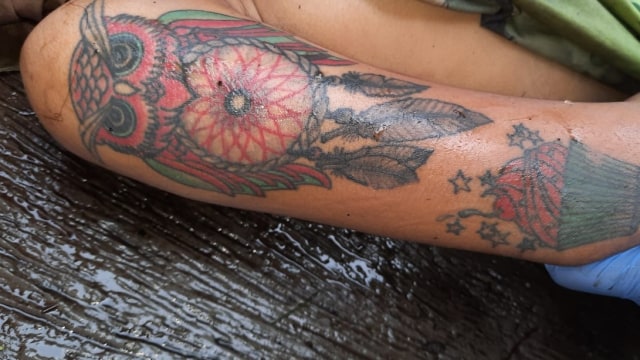 Petugas menunjukkan tato yang di tubuh mayat wanita yang ditemukan di Lembang, Foto: Dok. Istimewa