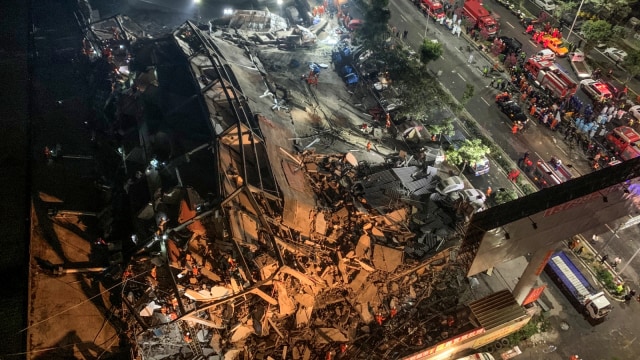 Tim penyelamat mencari korban yang selamat di puing-puing sebuah hotel yang runtuh di Quanzhou, di provinsi Fujian di Cina timur, Sabtu (7/3). Foto: STR / AFP