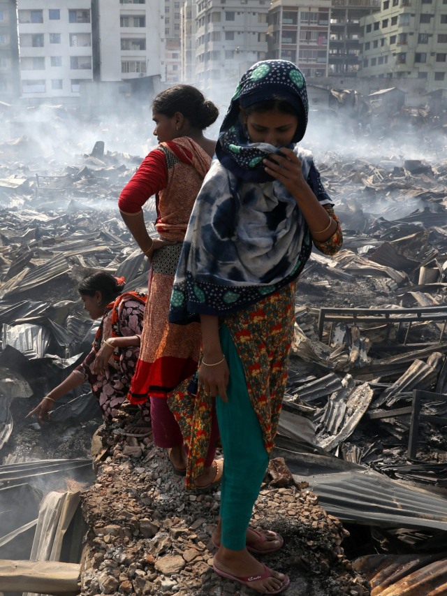 Warga beraktivitas diantara puing-puing bangunan pascakebakaran permukiman kumuh di Dhaka, Bangladesh. Foto: REUTERS / Mohammad Ponir Hossain