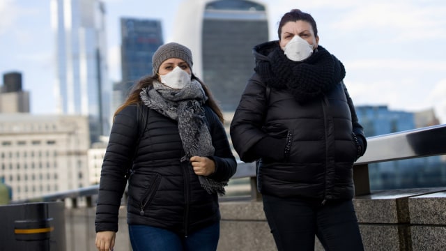 Sejumlah pejalan kaki mengenakan masker saat berjalan di London, Inggris. Foto: AFP/TOLGA AKMEN