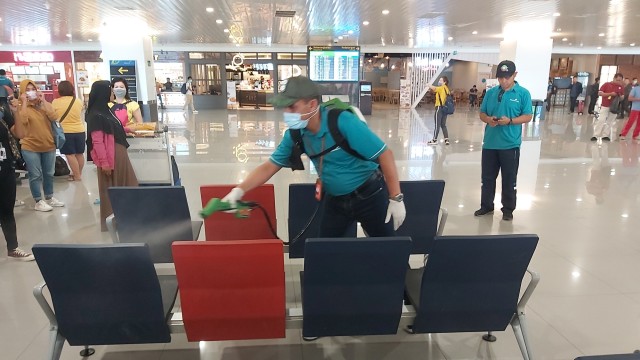 Petugas menyemprotkan desinfektan ke tempat duduk di areal Bandara Internasional Jendral Ahmad Yani Semarang. Foto: Afiati Tsalitsati/kumparan