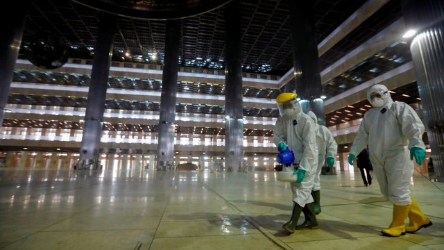 Petugas medis menyemprotkan cairan disinfektan di area Masjid Istiqlal, Jakarta Pusat, Jumat (13/3).  Foto: REUTERS / Willy Kurniawan