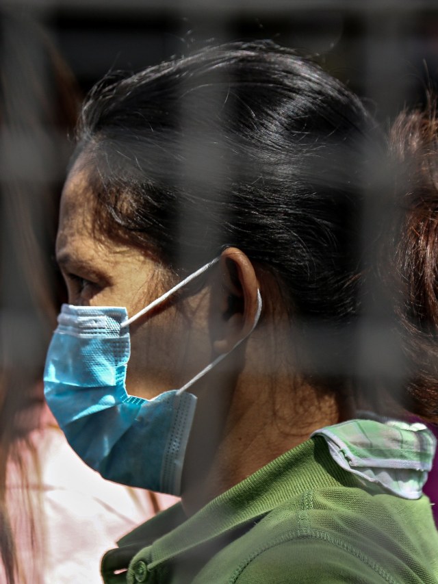 Salah satu penumpang mengenakan masker saat menunggu di Terminal Bus Pusat Araneta di Cubao di Manila, Filipina, Jum'at (13/3). Foto: AFP/MARIA TAN
