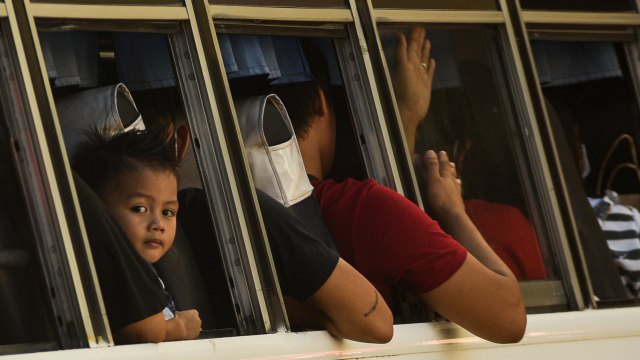 Seorang anak di dalam bus saat meninggalkan di Terminal Bus Pusat Araneta di Cubao di Manila, Filipina, Jum'at (13/3).  Foto: AFP/MARIA TAN