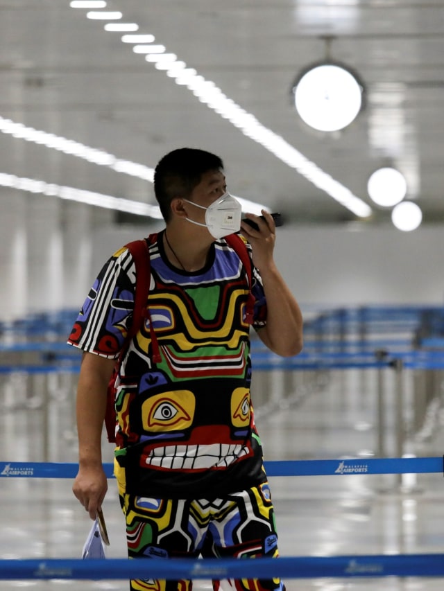 Penumpang menggunakan masker saat tiba di Bandara Internasional Kuala Lumpur, Malaysia. Foto: REUTERS / Lim Huey Teng