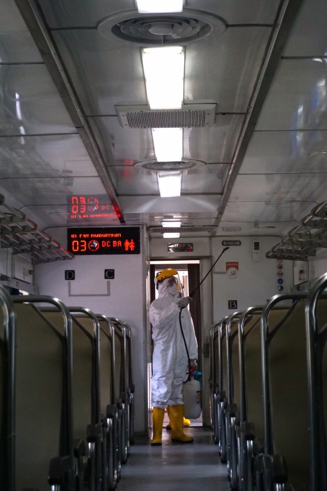 Seorang petugas menyemprotkan cairan disinfektan di dalam gerbong kereta api di Stasiun Pasar Senen, Jakarta, Minggu (15/3). Foto: Fanny Kusumawardhani/kumparan