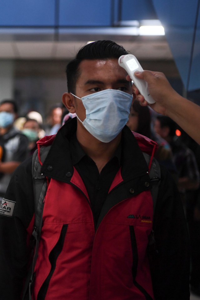 Petugas memeriksa suhu tubuh calon penumpang KRL Commuter Line di Stasiun Juanda, Jakarta, Senin (16/3). Foto: ANTARA FOTO/Wahyu Putro A