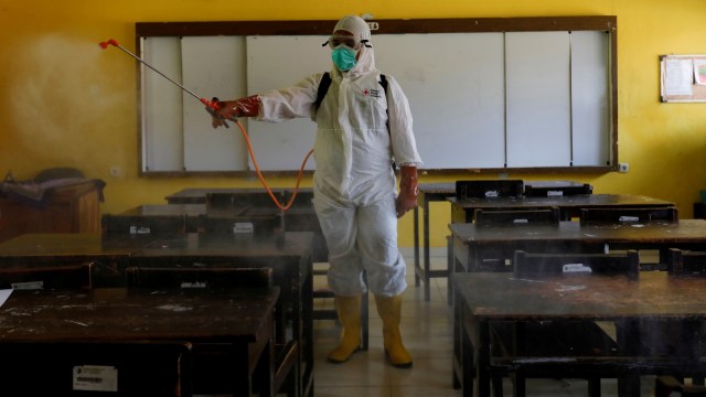 Relawan dari PMI menyemprotkan disinfektan pada ruang kelas di sebuah Sekolah di Jakarta, Senin (16/3). Foto: REUTERS/Willy Kurniawan