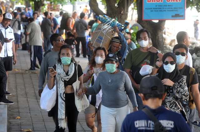 Warga dan wisatawan mengenakan masker di kawasan Pantai Sanur, Denpasar, Bali, Selasa (17/) Foto: ANTARA FOTO/Fikri Yusuf