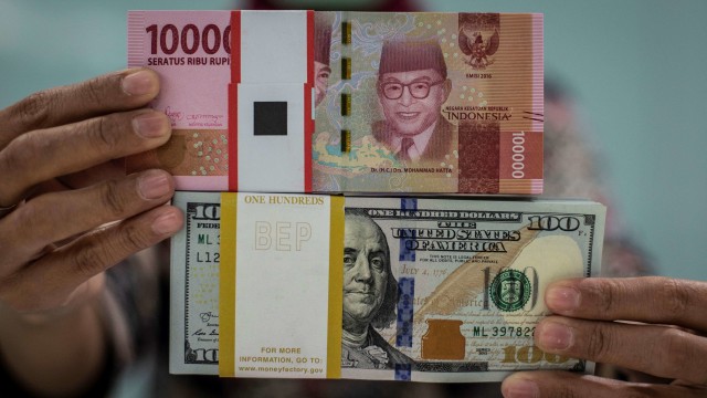 Karyawan menunjukkan uang rupiah dan dolar AS. Foto: ANTARA FOTO/Aprillio Akbar