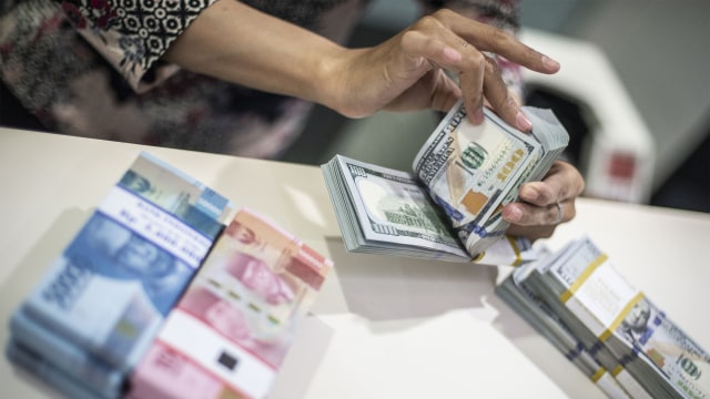 Karyawan menghitung uang dolar AS. Foto: ANTARA FOTO/Aprillio Akbar