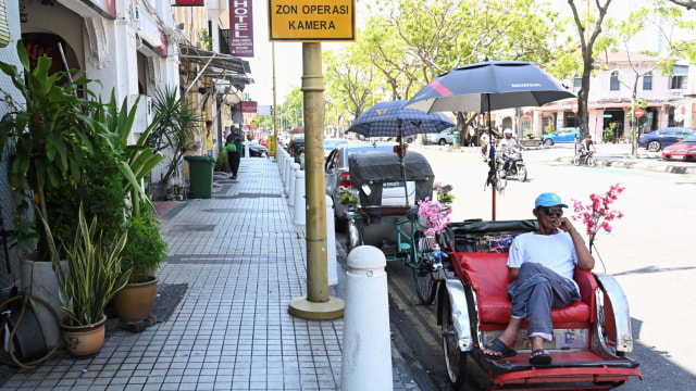 Seorang pengemudi becak menunggu pelanggan di sepanjang jalan di Penang, Malaysi, Rabu (18/3). Foto: AFP/GOH CHAI HIN
