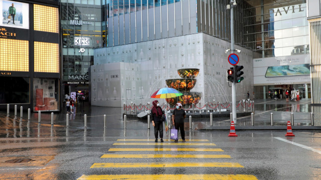 Warga menggunakan masker menunggu menyebrang di depan pusat perbelanjaan yang tutup di Kuala Lumpur, Malaysia, Rabu (18/3).  Foto: REUTERS / Lim Huey Teng