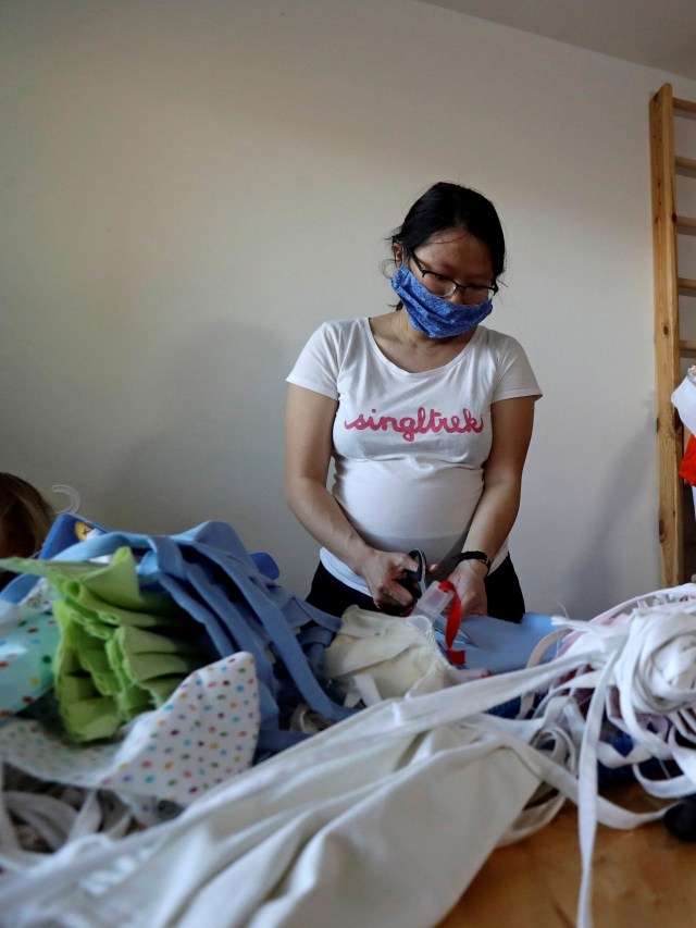 Warga memotong bahan masker buatan dari kain di Praha, Republik Ceko. Foto: REUTERS / David W Cerny