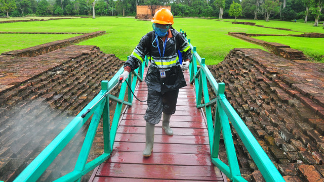 Petugas Balai Pelestarian Cagar Budaya (BPCB) Jambi menyemprotkan cairan disinfektan di halaman Candi Gumpung, Kawasan Percandian Muarajambi, Jambi. Foto:  ANTARA FOTO/Wahdi Septiawan