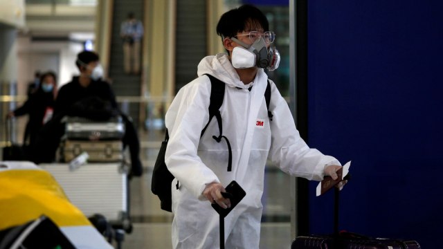 Seorang penumpang menggunakan pakaian pelindung dari plastik dan kacamata pelindung di Bandara Internasional Hong Kong, Hong Kong, Selasa (17/3). Foto: REUTERS/Tyrone Siu