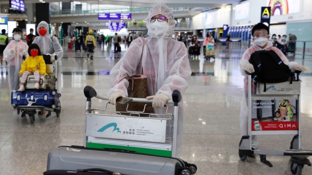 Sejumlah penumpang menggunakan pakaian pelindung dari plastik di Bandara Internasional Hong Kong, Hong Kong, Selasa (17/3). Foto: REUTERS/Tyrone Siu