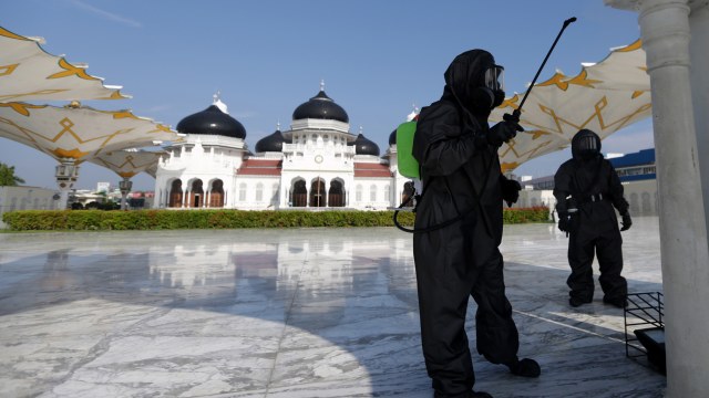 Personel Polda Aceh melakukan penyemprotan cairan disinfektan di Masjid Raya Baiturrahman, Banda Aceh. Foto: ANTARA/Irwansyah Putra