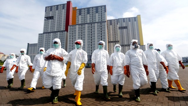 Personel PMI dengan pakaian hazmat bersiap menyemprotkan disinfektan ke Wisma Atlet di Kemayoran, Jakarta. Wisma Atlet akan difungsikan sebagai RS Darurat Corona. Foto: REUTERS/Ajeng Dinar Ulfiana