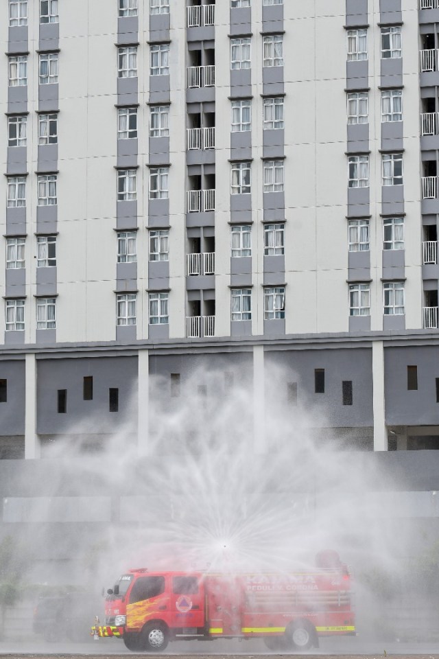 Relawan BNPB mengoperasikan mobil pemadam kebakaran untuk menyemprotkan disinfektan di kompleks Wisma Atlet, Kemayoran, Sabtu (21/3). Foto: ANTARA/M. Risyal Hidayat