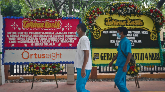 Warga berdiri di depan karangan bunga dukungan untuk tenaga medis dan staf Rumah Sakit Penyakit Infeksi (RSPI) Sulianti Saroso di Jakarta. Foto: ANTARA FOTO/Aditya Pradana Putra