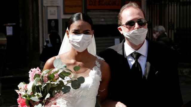 Pasangan pengantin menggunakan masker yang menikah saat Italia lockdown karena virus corona. Foto: REUTERS/Ciro De Luca