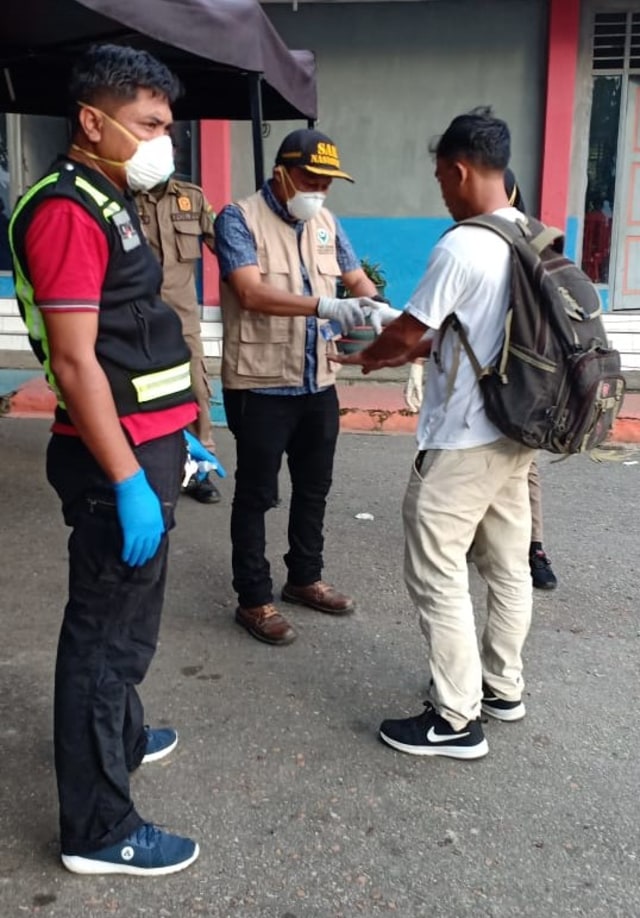Petugas medis di Pelabuhan Tobaku, memberikan hand sanitizer kepada penumpang yang hendak menyeberang ke pelabuhan Wajo. Foto: Lukman Budianto/kendarinesia.